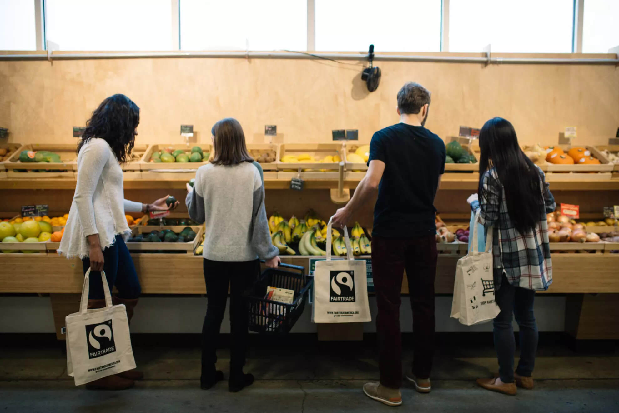 Shoppers in grocery store buying bananas and produce.